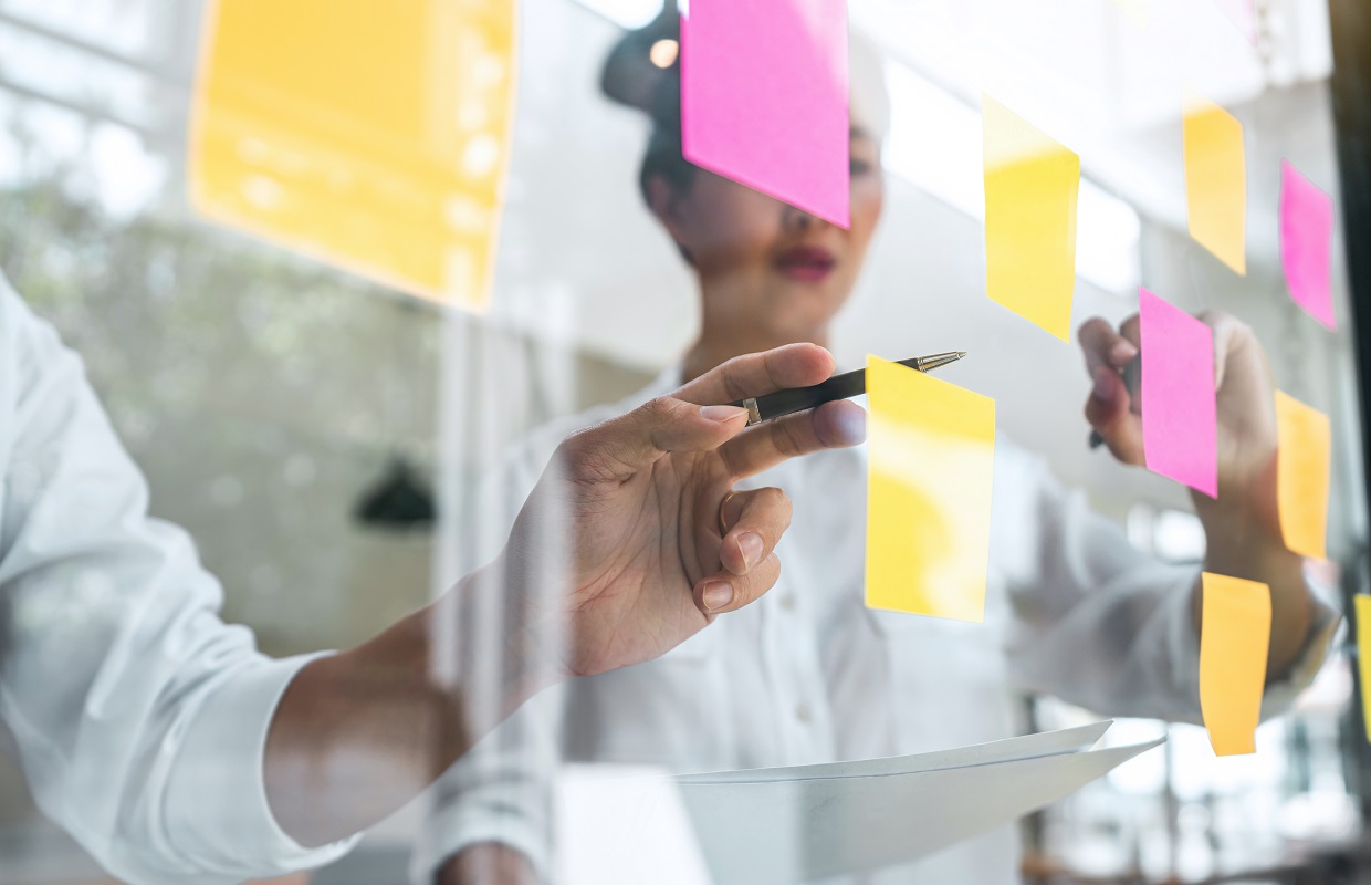 Young people write on a glass wall and use post it notes to plan a strategy